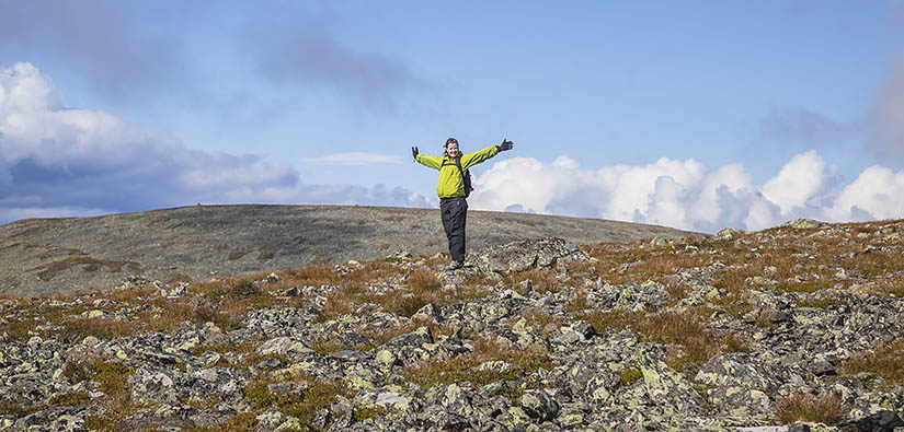 Nainen tuulettaa tunturin huipulla.