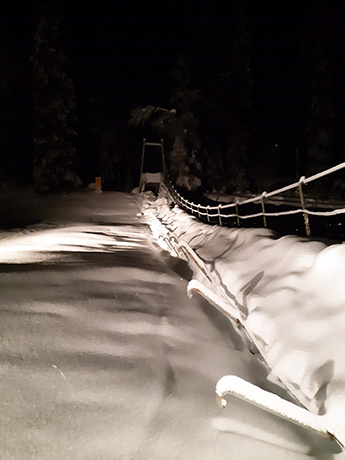 Runsaan lumen peittämä toiselta puolelta romahtanut riippusilta.