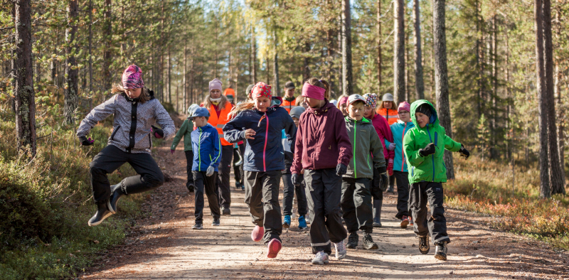 Children are running and jumping on a forest road.