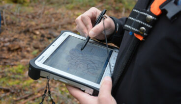 En av Forststyrelsens medarbetare använder ett geografiskt informationssystem på en bildskärmsenhet.