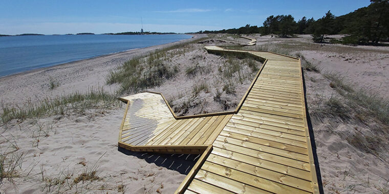 Poikittaisista laudoista tehty kulkutie, lankkupolku, hiekkarannalla Hangon Tulliniemenrannassa.