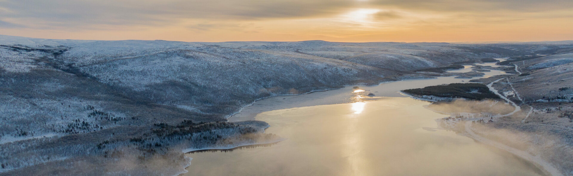 Ilmasta kuvattu talvinen maisema Utsjoelta, kuvassa näkyy vesistö ja tuntureita.