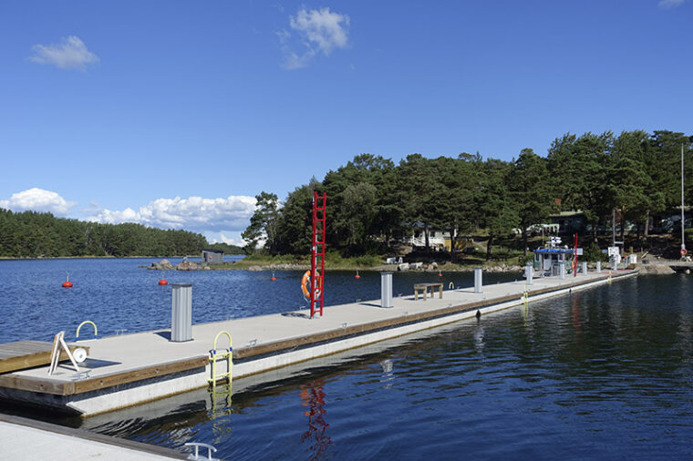 Pitkä venelaituri. Taustalla näkyy saari ja rakennuksia.