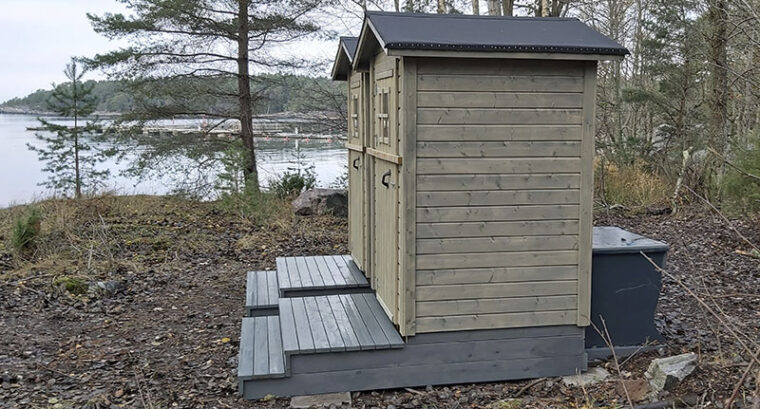 Two wooden dry toilets side by side close to shore.