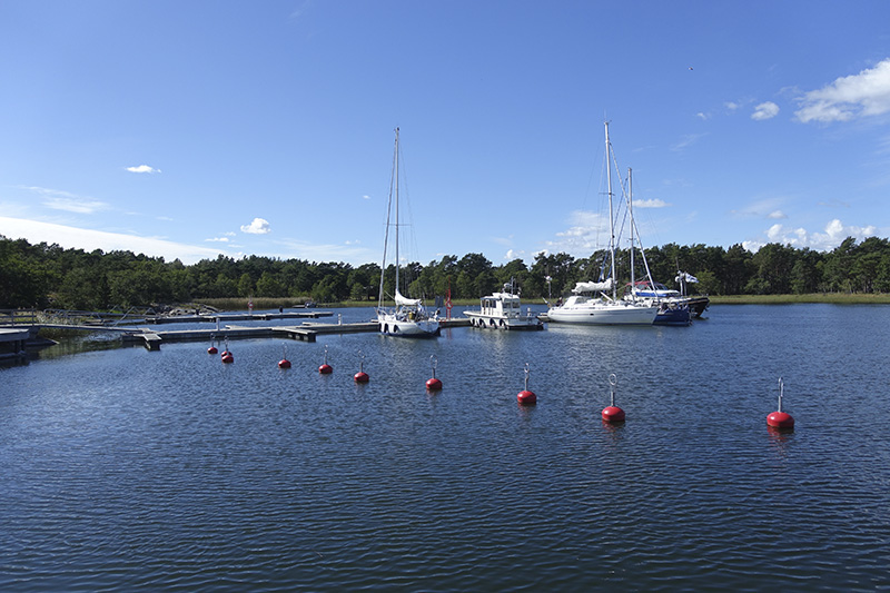 Lång brygga med flera förtöjda båtar. Längre bort från bryggan finns bojar.