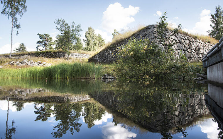 Kivestä ladottuja matalia muureja veden äärellä.