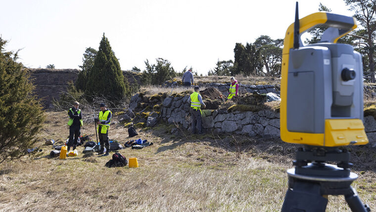 Arbetare vid gammal stenmur på Svartholms fästningsö. I förgrunden en mätningsapparat.