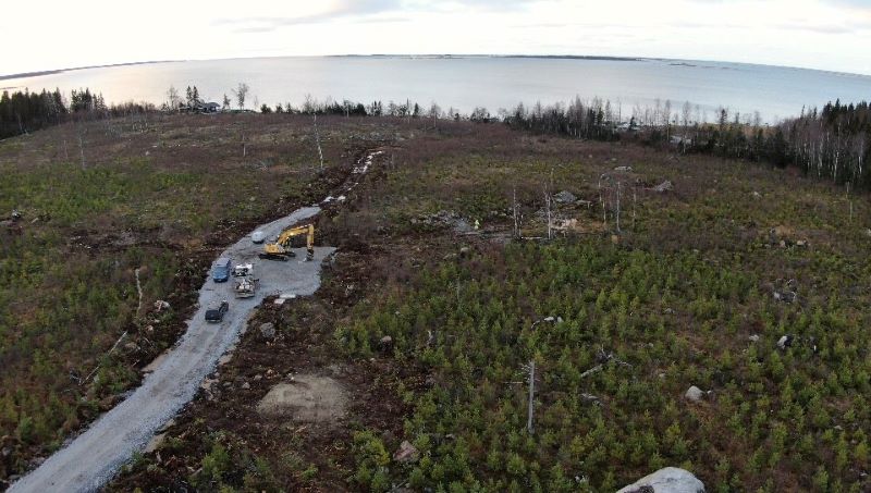 Dronekuva työmaasta, jossa tasoitetaan tuulimittausmaston paikkaa lähellä meren rantaa.