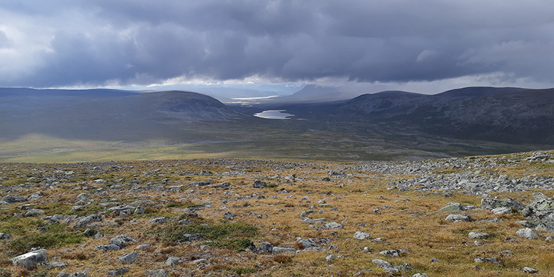 Treeless fells and a lake inbetween,Tthick, dark clouds hanging over the landscape.