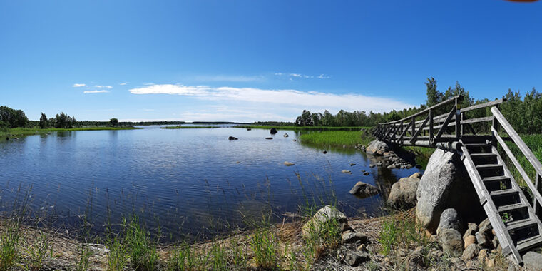 En sommarvy från stranden till näraliggande låga, små öar i havet.