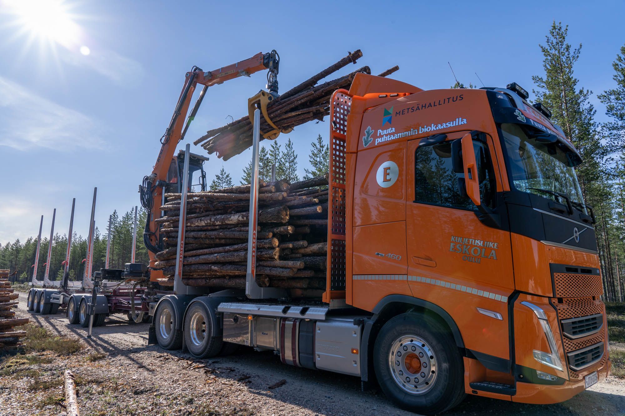 Puutavara-auto kuvattuna edestä ja kyytiin ollaan lastaamassa juuri puita. 