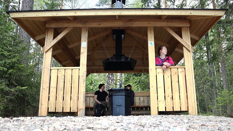 A wooden shelter wiht an iron stove in the forest.