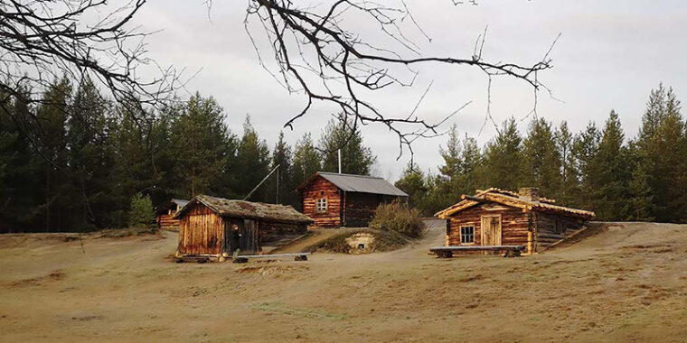 Maalaamattomia, vanhoja, pieniä hirsirakennuksia hiekkarinteessä päädyt samaan suuntaan. Kaksi rakennuksista osin rinteen sisään rakennettuja.