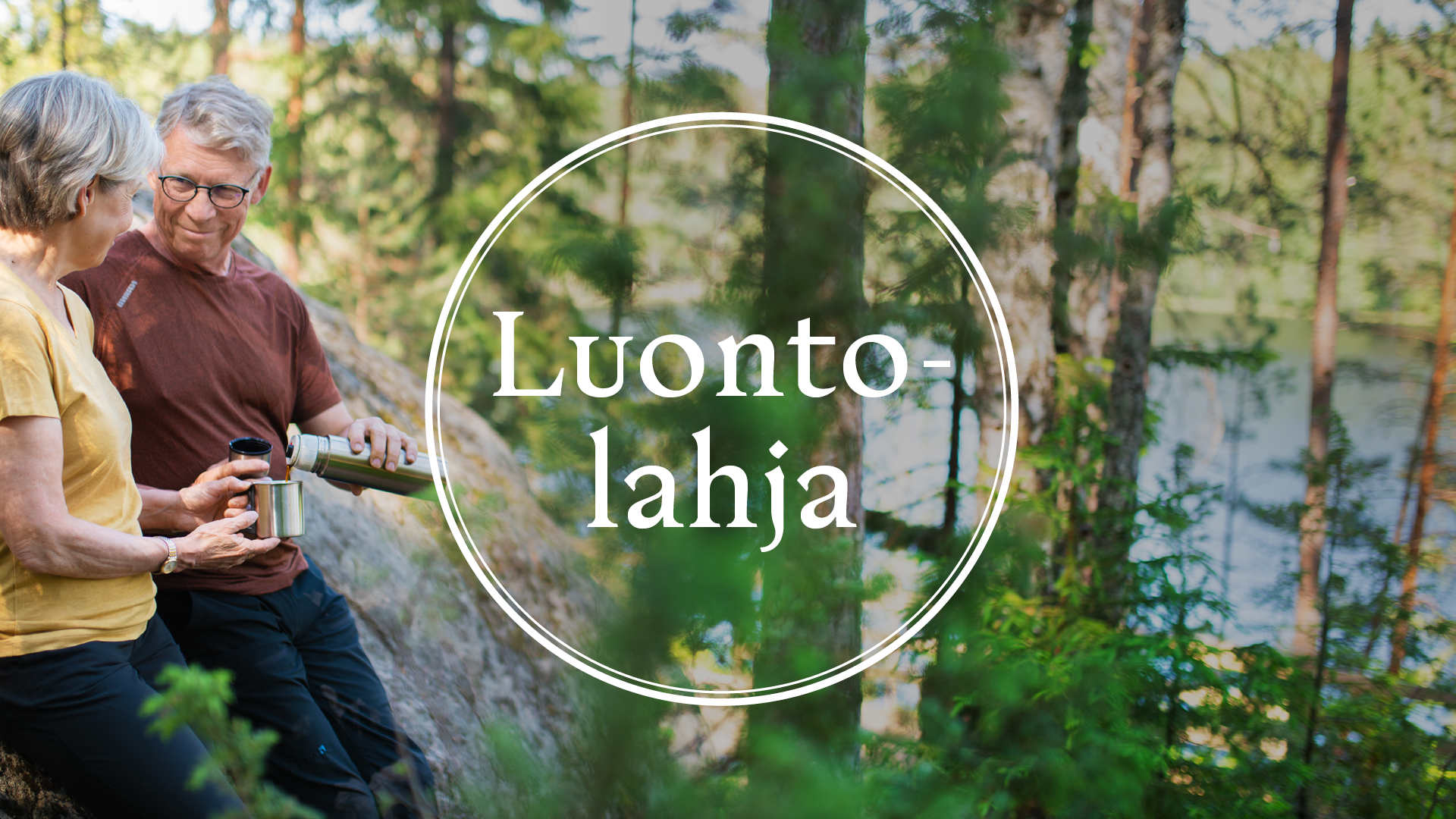 Kesäinen maisema metsästä, taustalla näkyy järvi ja sivustalla kaksi henkilöä retkeilyvaatteissa nauttivat termospullosta kahvia. Keskellä kuvaa ympyrä jonka keskellä teksti Luontolahja.
