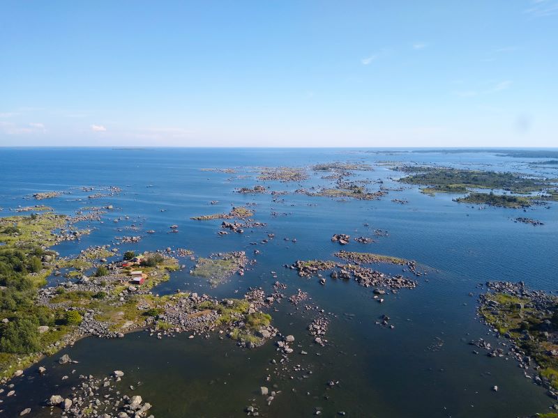 Maisema merelle, jossa näkyy kivikkoisia pieniä saaria ja kareja. Yhdessä saaressa on rakennuksia.