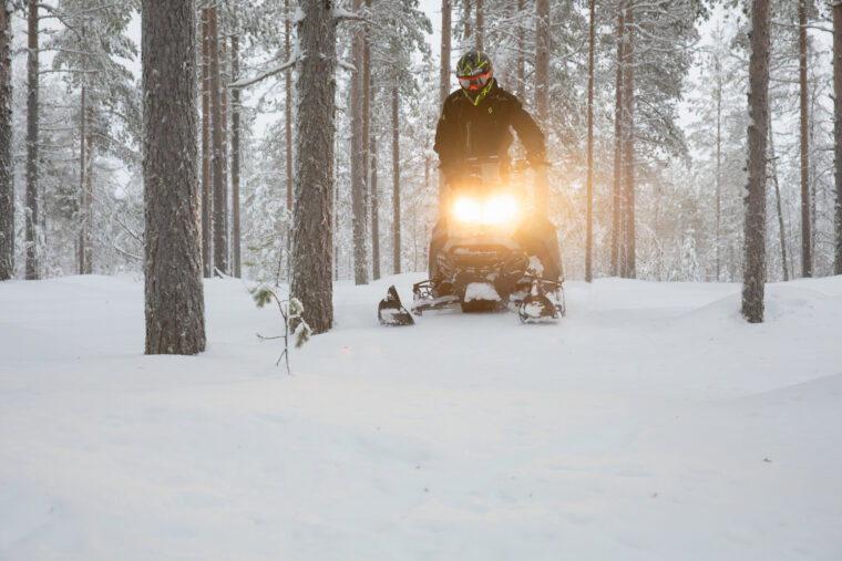 Moottorikelkkailija talvisessa metsässä.