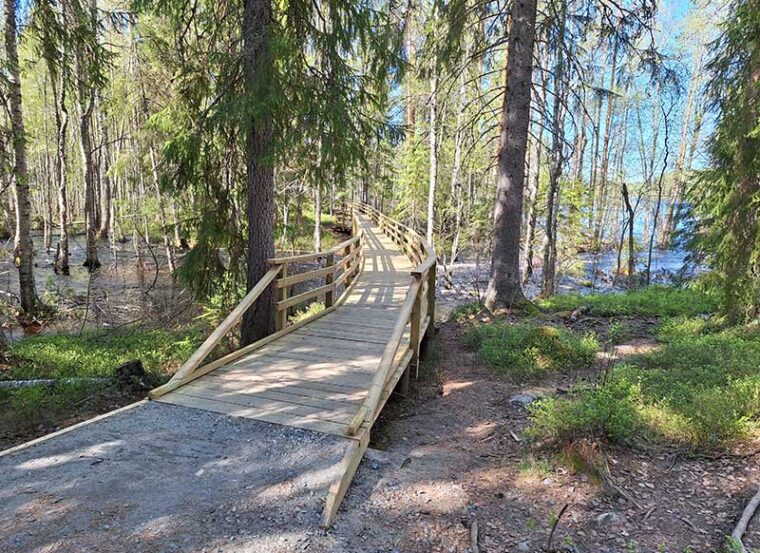 Leveä puusilta vie tulvivan joen yli.