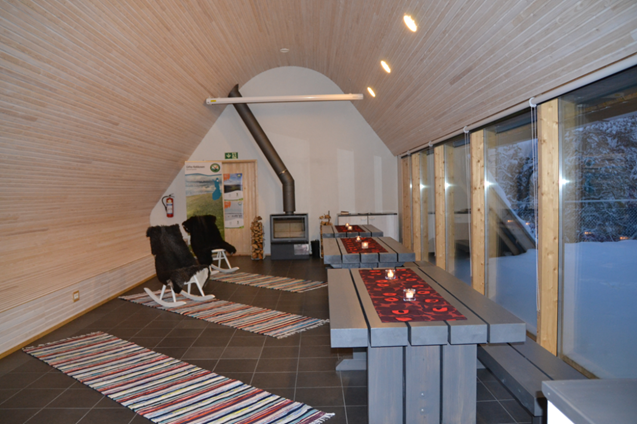 Tupa sisältä. Tuvassa on takka, keinutuolit, pöydät ja penkit.
