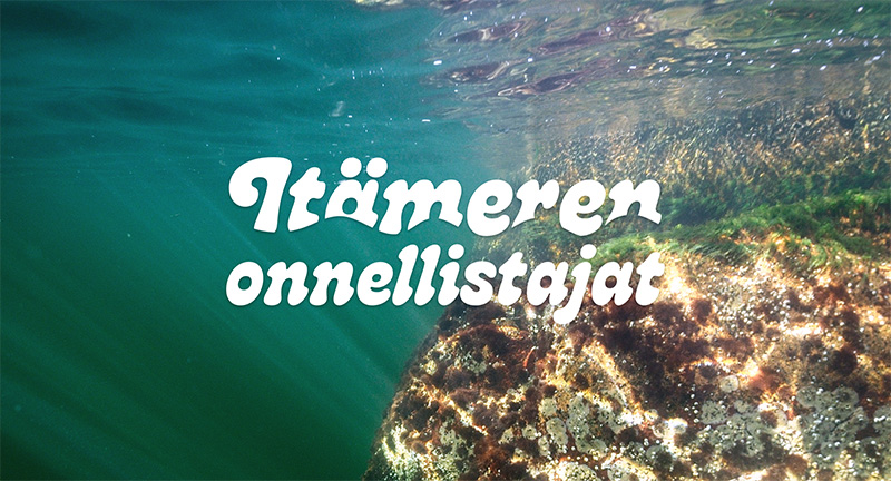 En undervattensbild av en klippa där färgglada alger växer. Ovanpå bilden finns texten Itämeren onnellistajat.