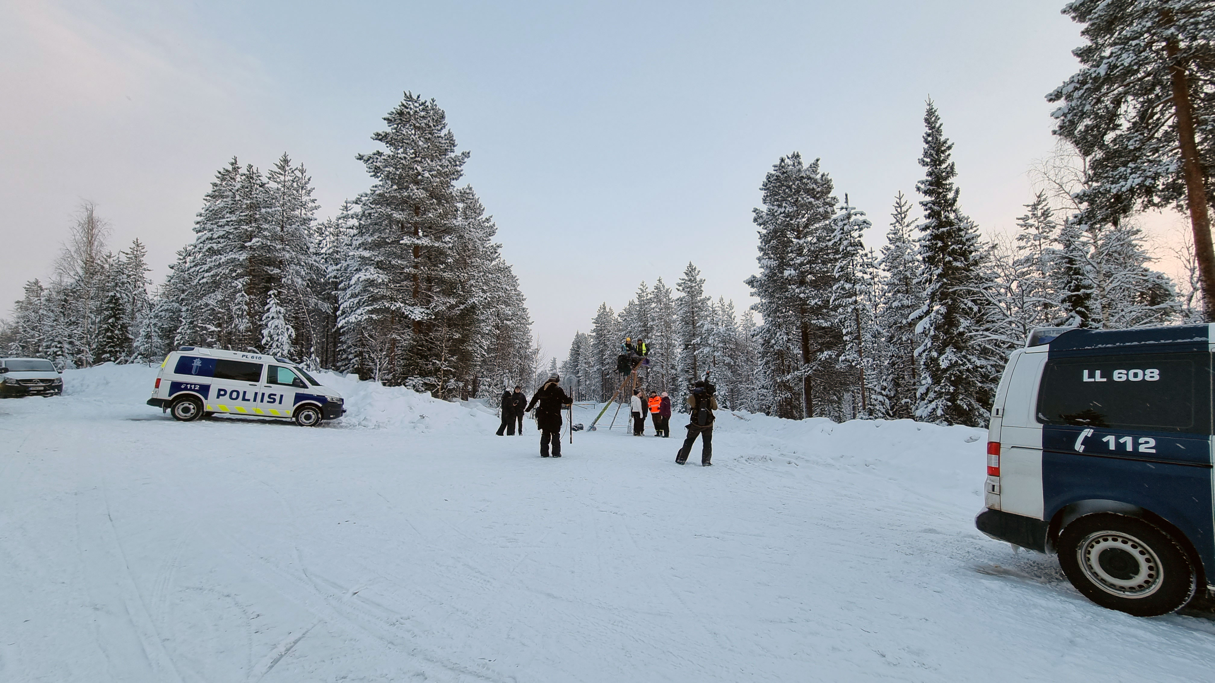 Talvella tienristeyksessä metsän keskellä henkilöitä ja poliisiautoja.