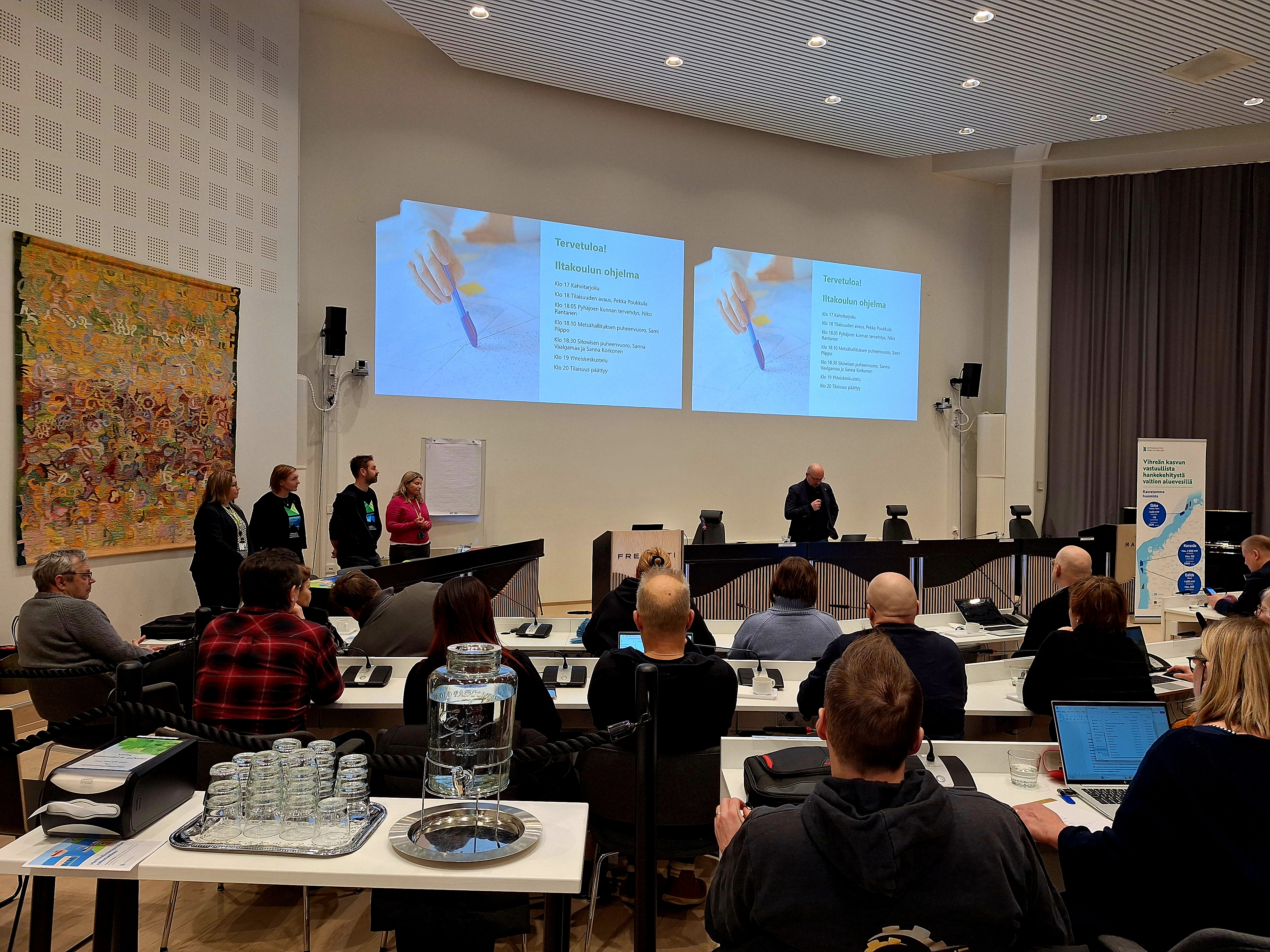 Raahen valtuuston puheenjohtaja Pekka Pukkula avaa Merituulivoimanhanke Ebban iltakoulutilaisuuden Raahessa 12.2.2026. Paikalla valtuustot Pyh&auml;joelta ja Raahesta sek&auml; esitysten pit&auml;j&auml;t Mets&auml;hallituksesta ja YVA-konsulttikumppani Sitowiselta.