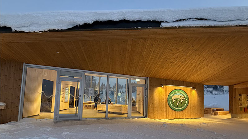 Puinen yksikerroksinen rakennus, jonka seinässä on Pallas-Yllästunturin tunnus. Seinässä on myös aukko, jonka viereiselle seinälle on kiinnitetty erilaista tietoa. Isoista lasi-ikkunoista näkee valaistuun tilaan, jossa on ihmisiä.