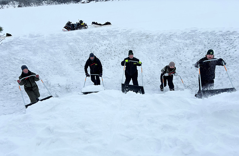 Viisi vapaaehtoista kolaa lunta korkeaksi kinokseksi.