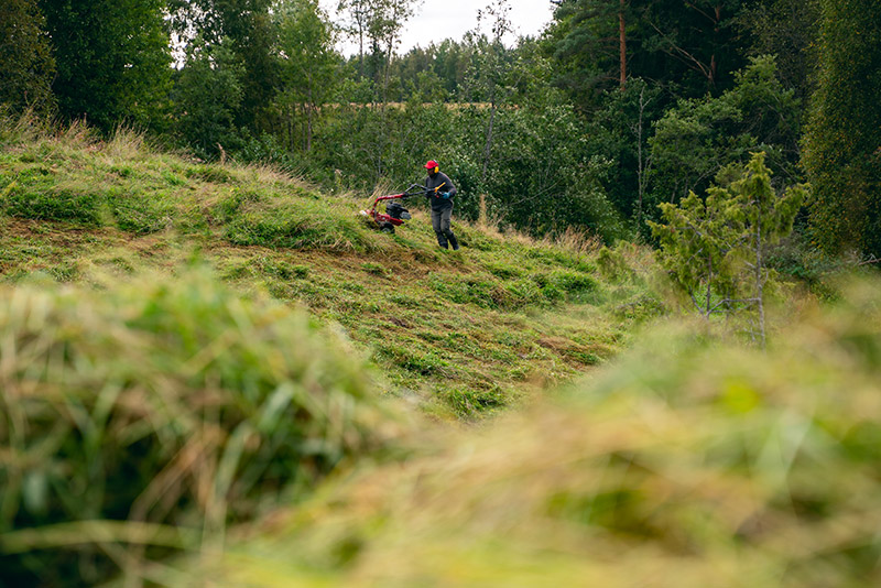 Ihminen niittää niittyä koneella.