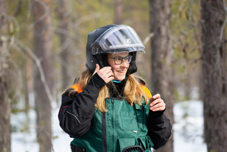 Moottorikelkkailija laittaa kypärää päähänsä.