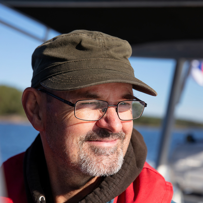 Kasvokuva miehestä veneessä. Miehellä on tyytyväinen ilme.