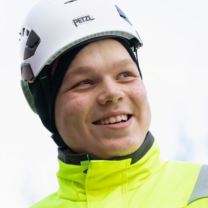 Nuori poika työvaatteet päällä ja kypärä päässä.