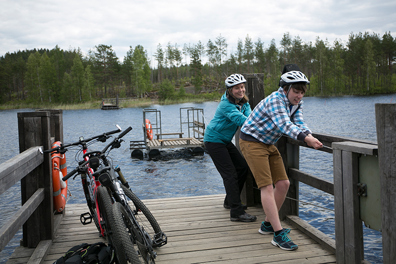 Kaksi pyöräilijää on laiturilla ja kiskoo vetolossia lähemmäksi laituria.
