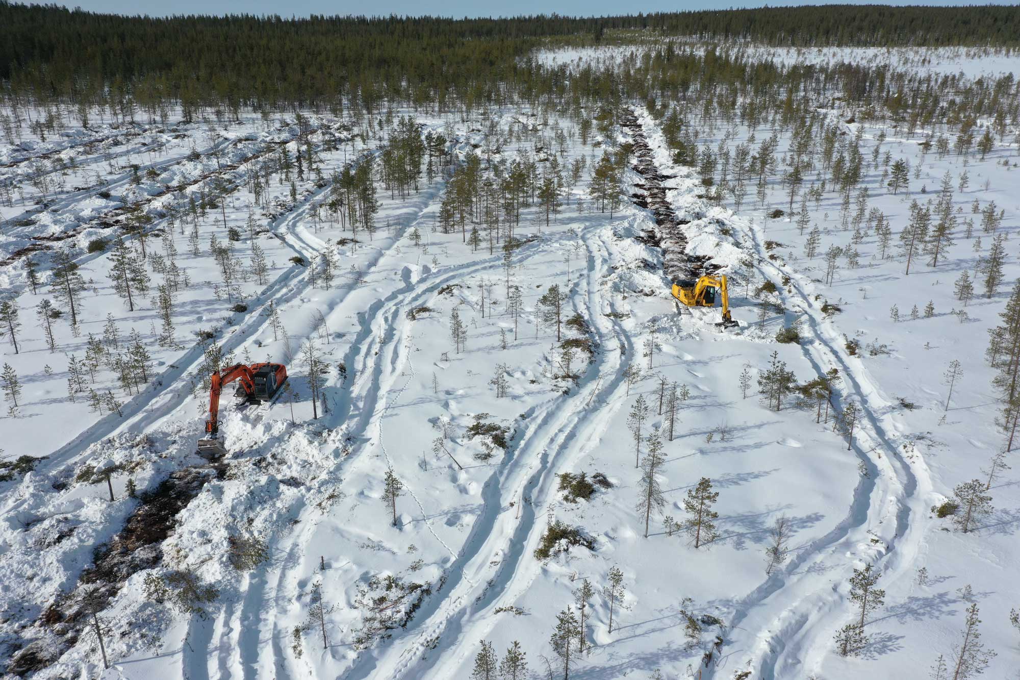 Suon ennallistamista talvella ja kaivinkoneita täyttämässä ojia.