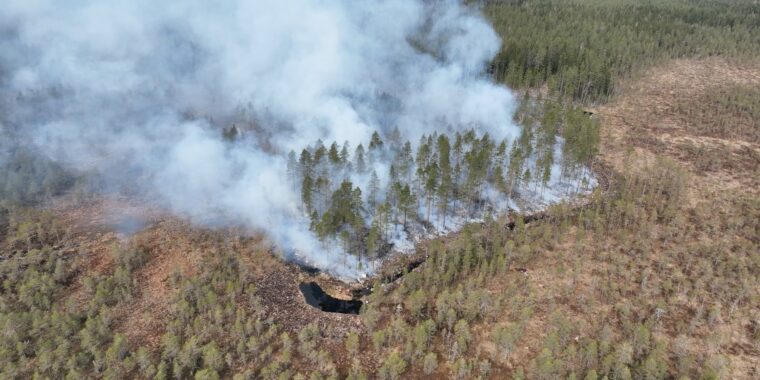 Ilmakuvaa metsäsaarekkeesta jota poltetaan ja savua nousee.