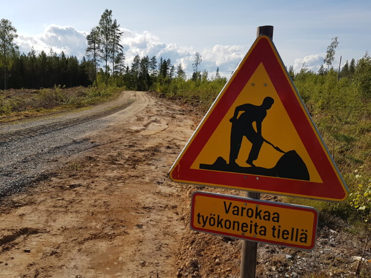 Tietyömaa ja kyltti "varokaa työkoneita tiellä".