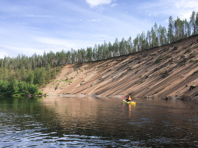 Retkeilij&auml; melomassa jyrk&auml;n hiekkarannan tuntumassa.