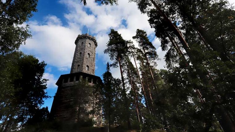 Graanittinen näkötorni kesäisen metsämaiseman keskellä.